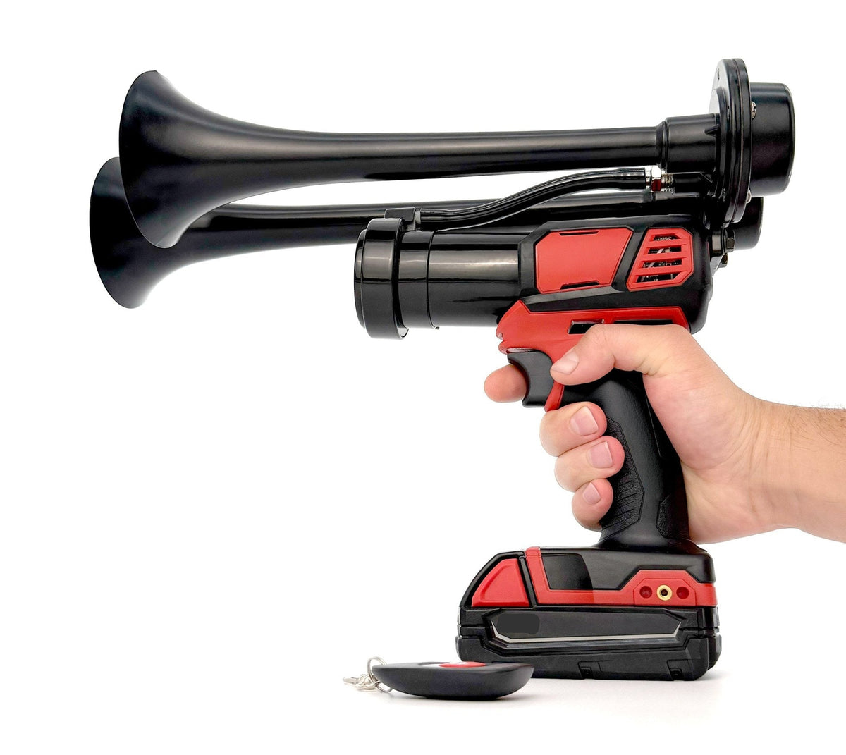 Hand holding the black dual trumpet train horn by the grip, wireless remote resting at its base