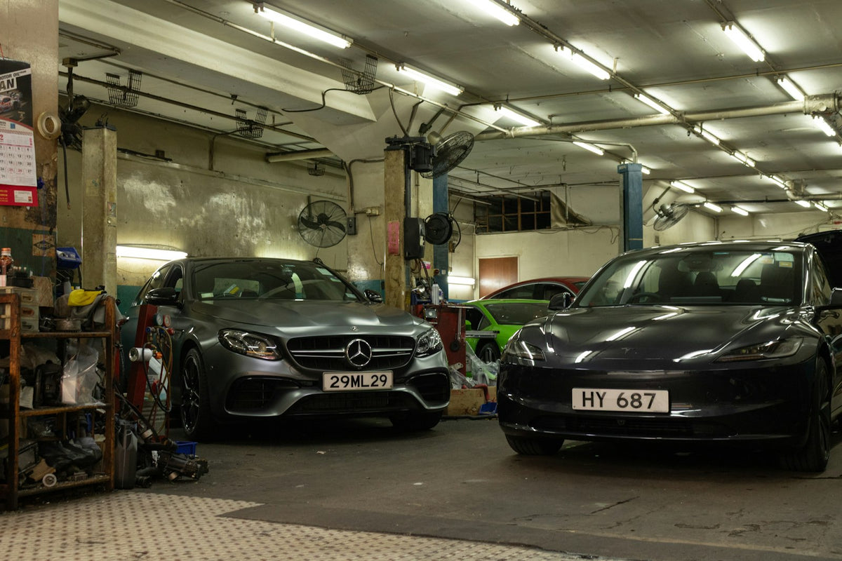 Gas and electric side by side: a Mercedes Benz and Tesla vehicles parked inside a working automotive repair garage in Hong Kong.