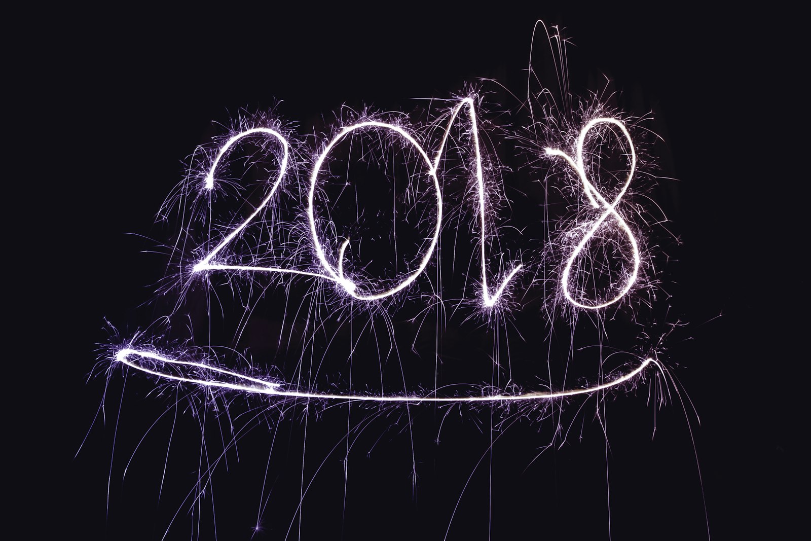 Bright multicolored fireworks bursting over a dark night sky during a New Year's Eve midnight celebration