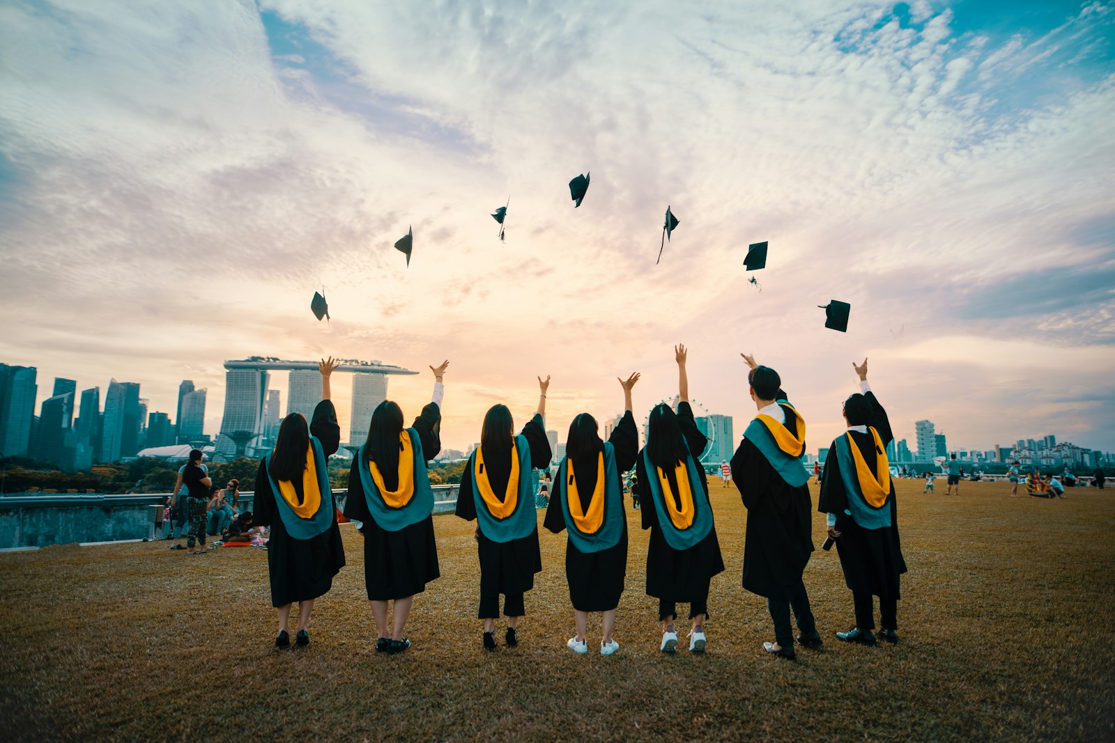 Group of graduates in caps and gowns tossing their mortarboards into the air to celebrate graduation