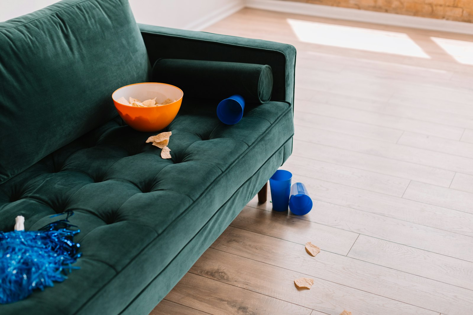 A cozy game-day watch party setup with a green couch, bowls of popcorn and snacks, and drinks laid out in front of a television.