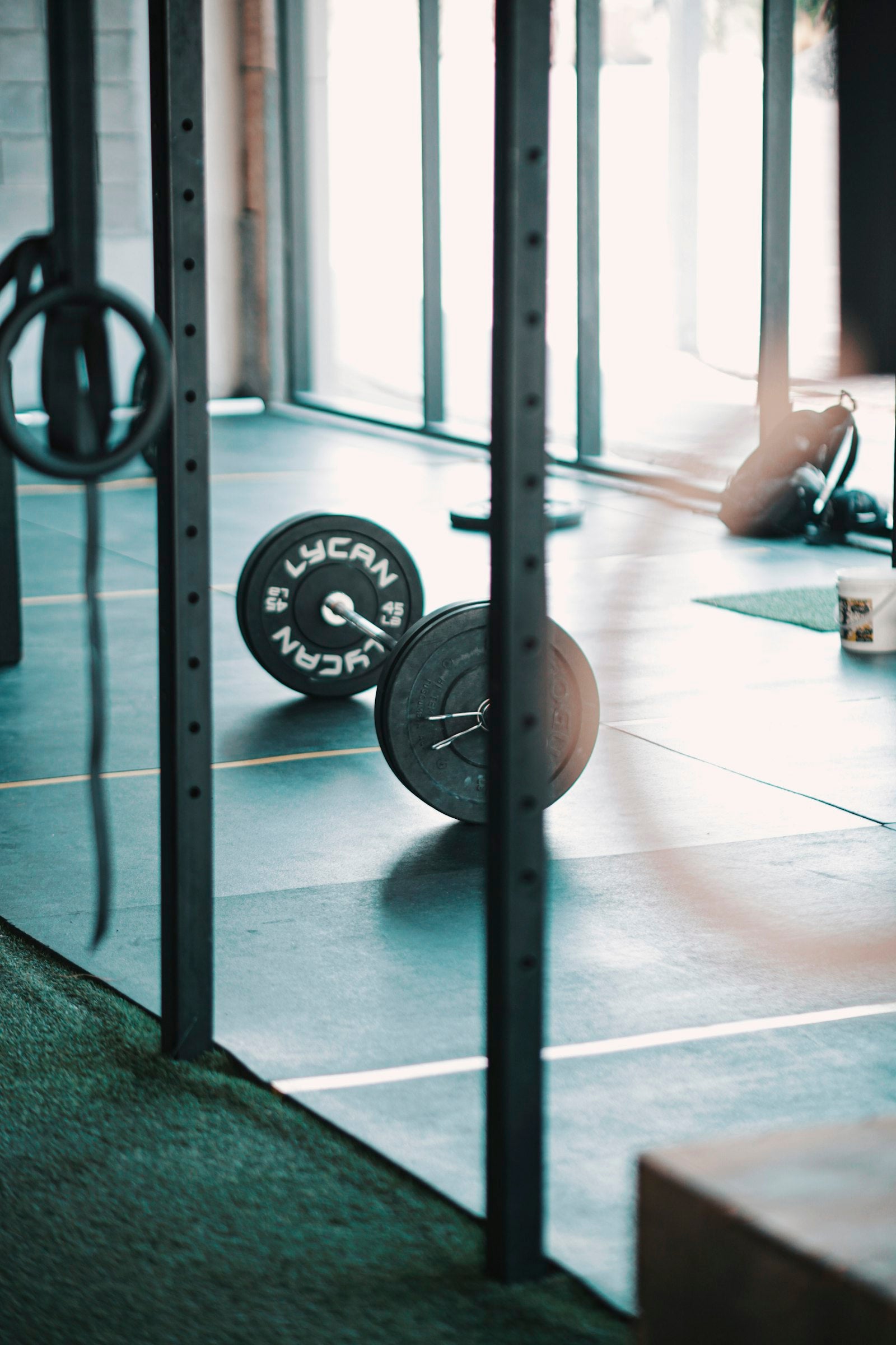 Loaded barbell with stacked weight plates on the floor of a functional-fitness gym, ready for a workout