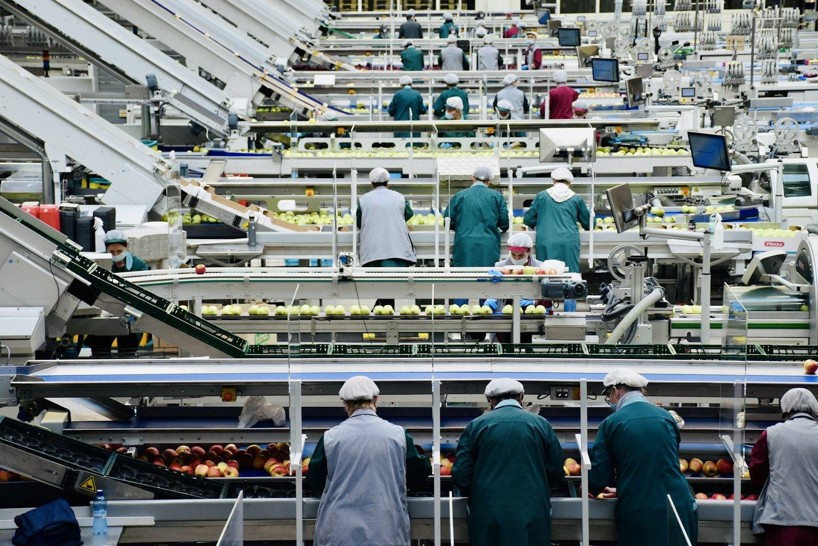 Workers on a manufacturing floor among industrial machinery during a shift at a factory plant