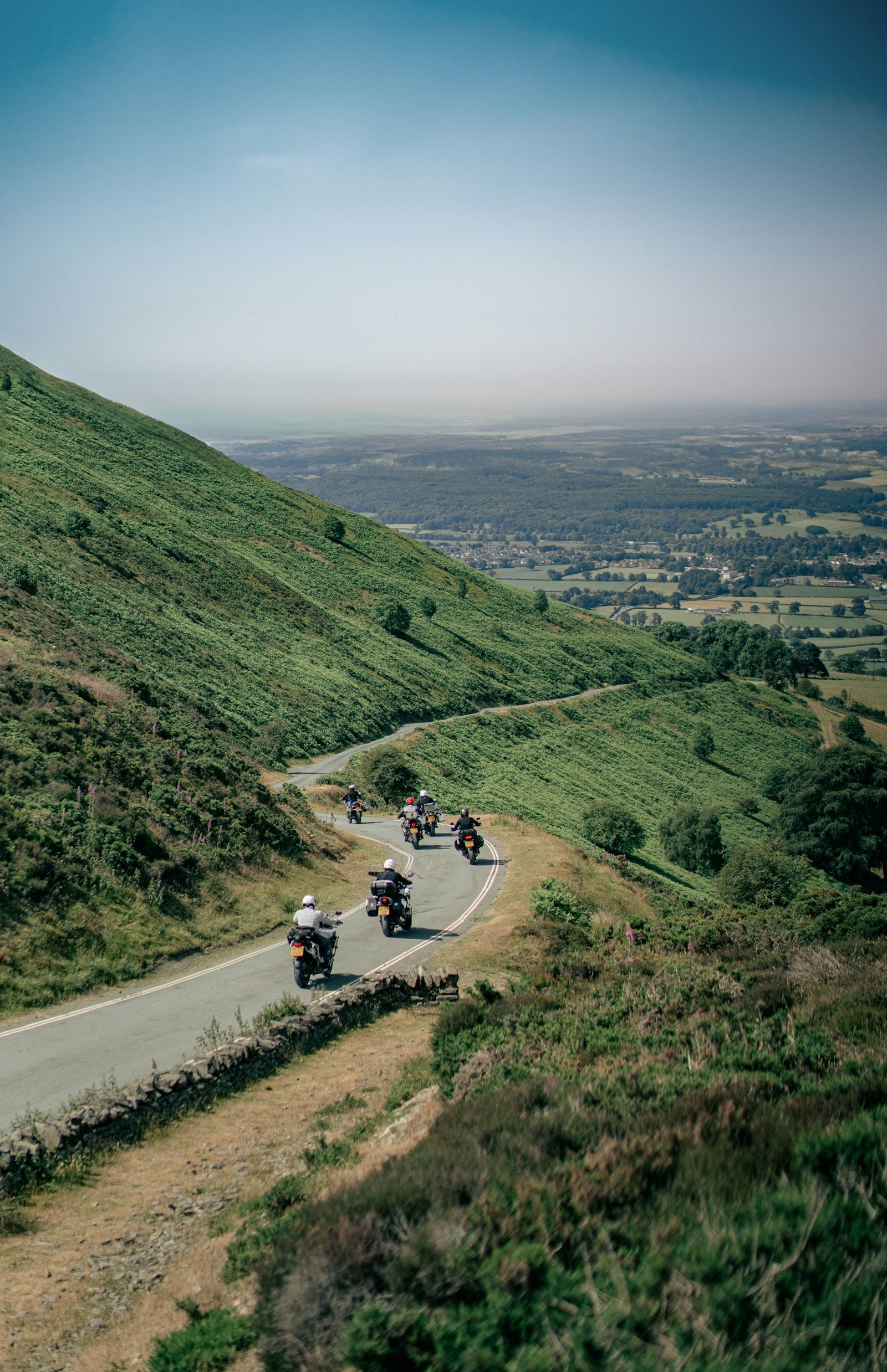 A group of motorcycle riders cruising in formation down a winding mountain road on a summer group ride