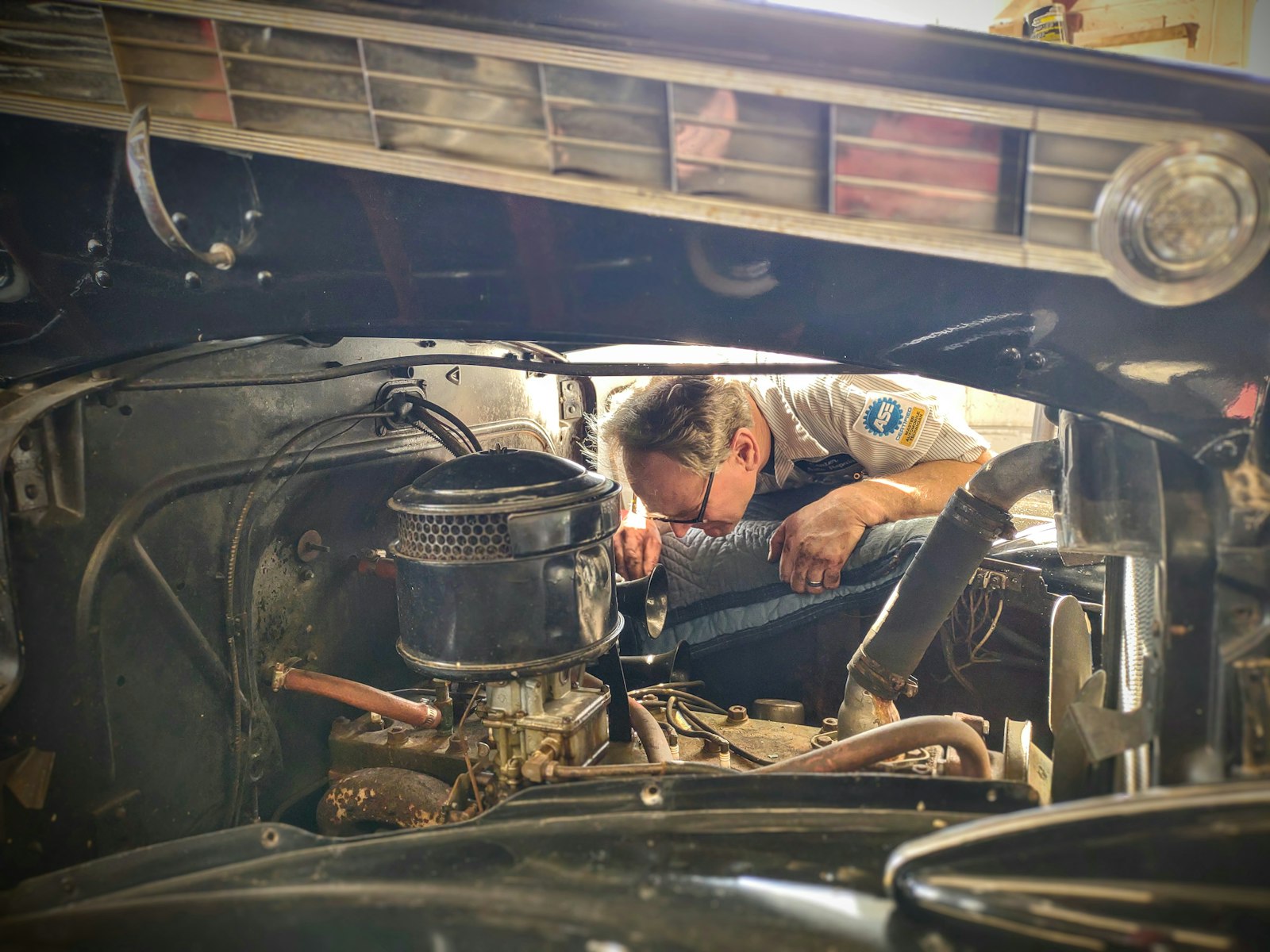 A man focused on repairing a truck engine in a home garage workshop surrounded by tools — a hands-on dad in his element