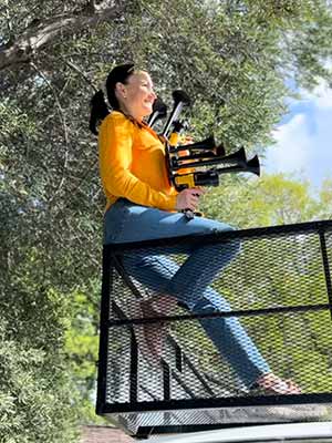 girl with two dewalt train horns playing on top of the car