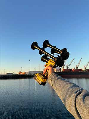 someone with Dewalt Train Horn aimed to the large cargo ship
